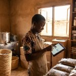 Jeune entrepreneur agroalimentaire camerounais utilisant une tablette dans son atelier