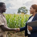 Jeune agriculteur camerounais serrant la main d une conseillère de banque devant un champ